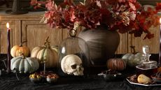 Table set with pumpkins, candles, skills and fall foliage for Halloween
