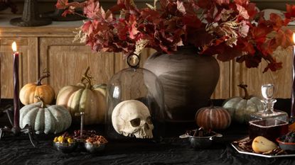 Table set with pumpkins, candles, skills and fall foliage for Halloween