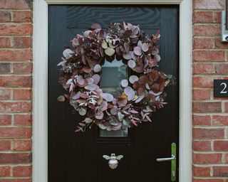wreath hanging on front door made of eucalyptus leaves