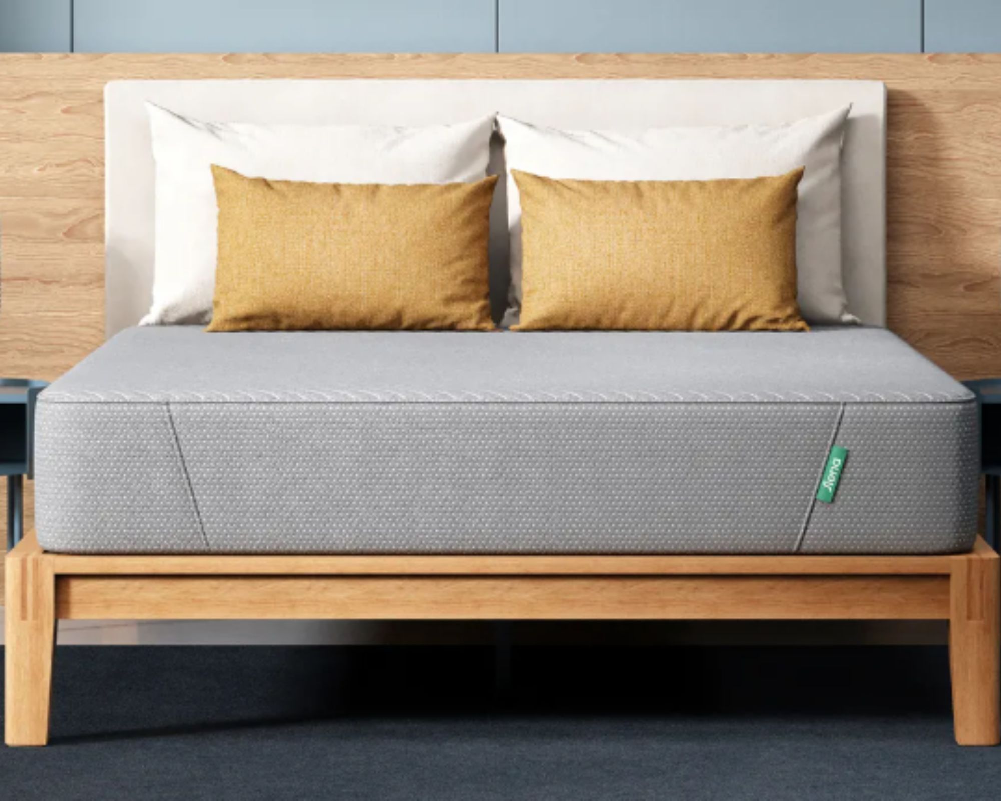 Grey Siena memory foam mattress with white and yellow cushions and pillows on a wooden bedframe with white headboard, and wood and blue panelled wall behind.