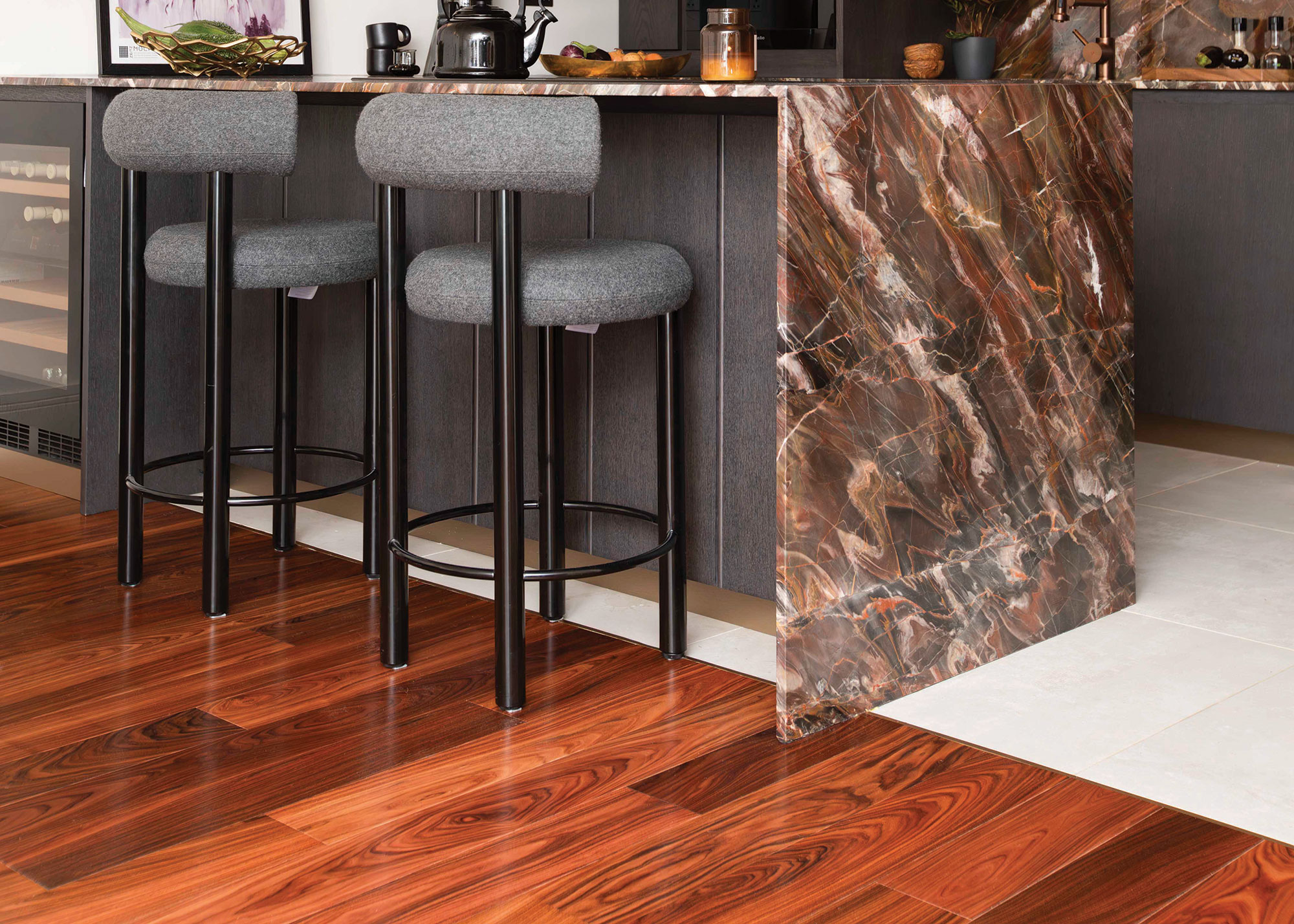 dark toned narrow plank wooden flooring in small open plan kitchen with waterfall island