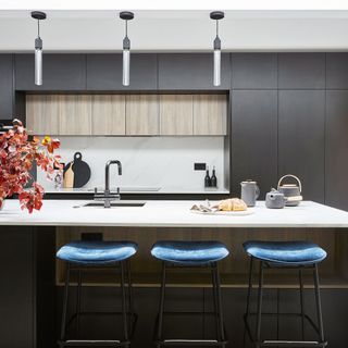 kitchen dinning area with black wall white counter and blue bar stools