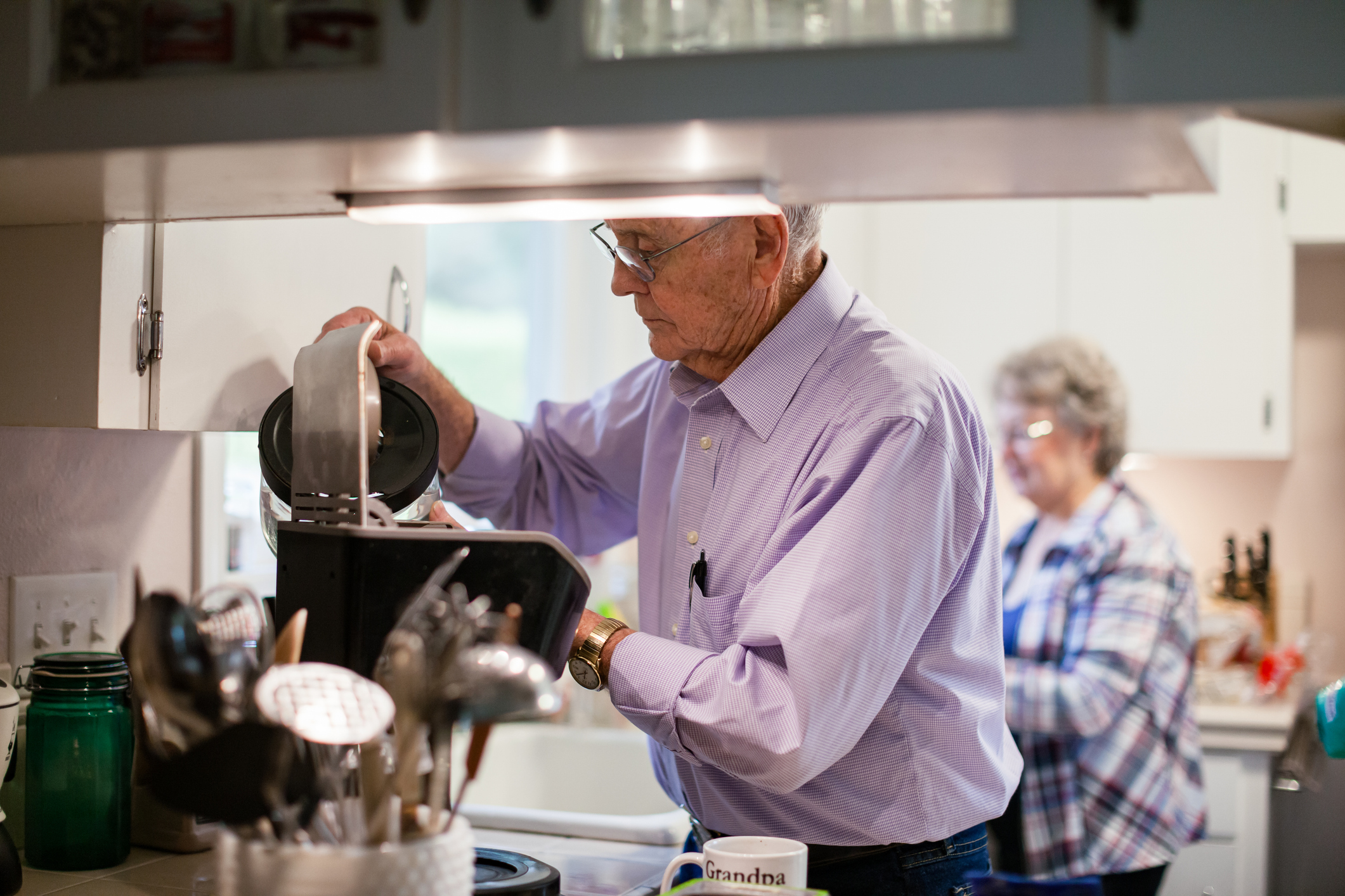 A couple in their 80s making coffee in their kitchen.