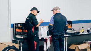 Two mechanics discuss something over a toolbox