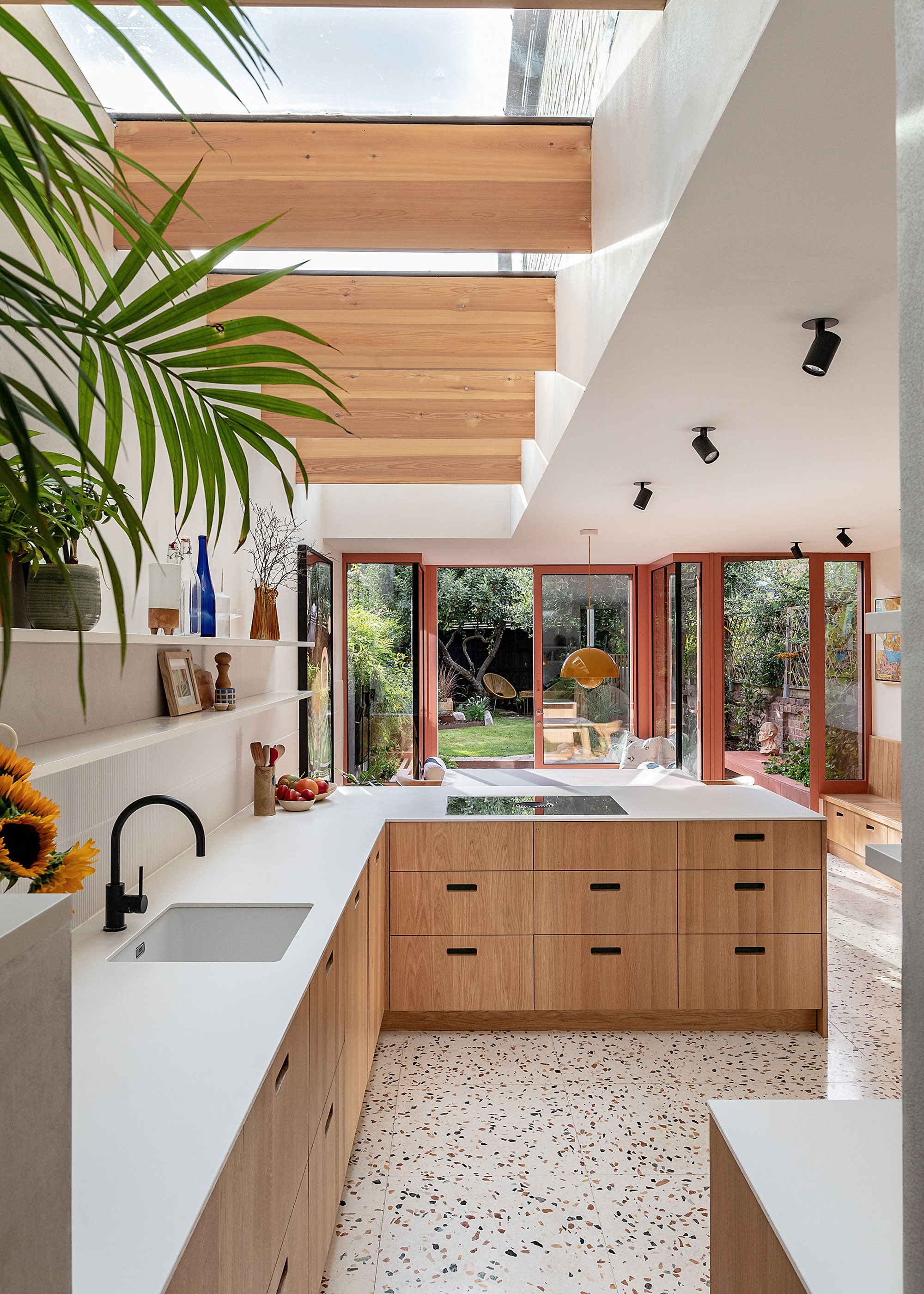 L-shaped kitchen in small kitchen extension with red sliding doors and terrazzo flooring