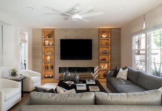 family living room with wall cut outs and lit alcove shelves with neutral sofas and white club armchairs