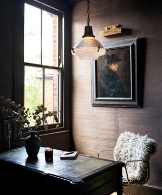 desk with glass pendant light above and picture light above artwork