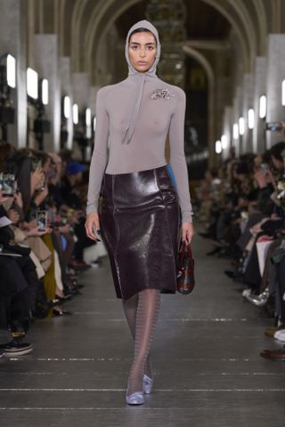 Tory Burch model wearing a leather skirt, hooded top, and brooch