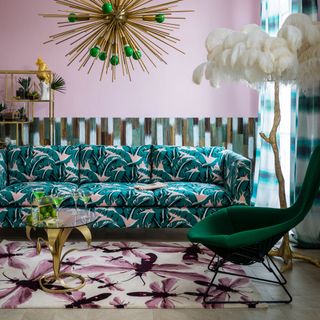 pink living room with green floral sofa and white feather lamp