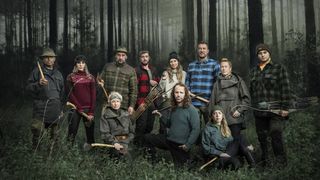 The contestants of Alone UK season 1 assembled in a dark forest. 