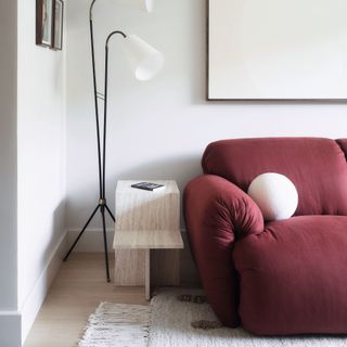Maroon sofa in living room, ball boucle cushion, side table, lamp