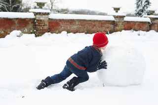 A child rolling a large ball of snow.