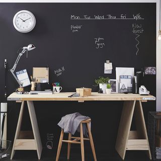 blackboard on wall with lamp on wooden desk and clock