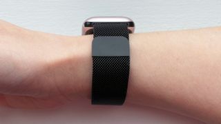 A black-coloured metal mesh watch strap wrapped around a woman's wrist.