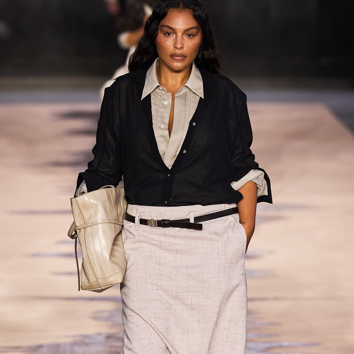 A model on the Hugo Boss runway wearing a black cardigan and white belted skirt