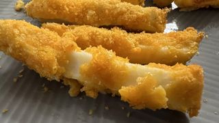 A close up image of a mozzarella stick coated in Cheetos
