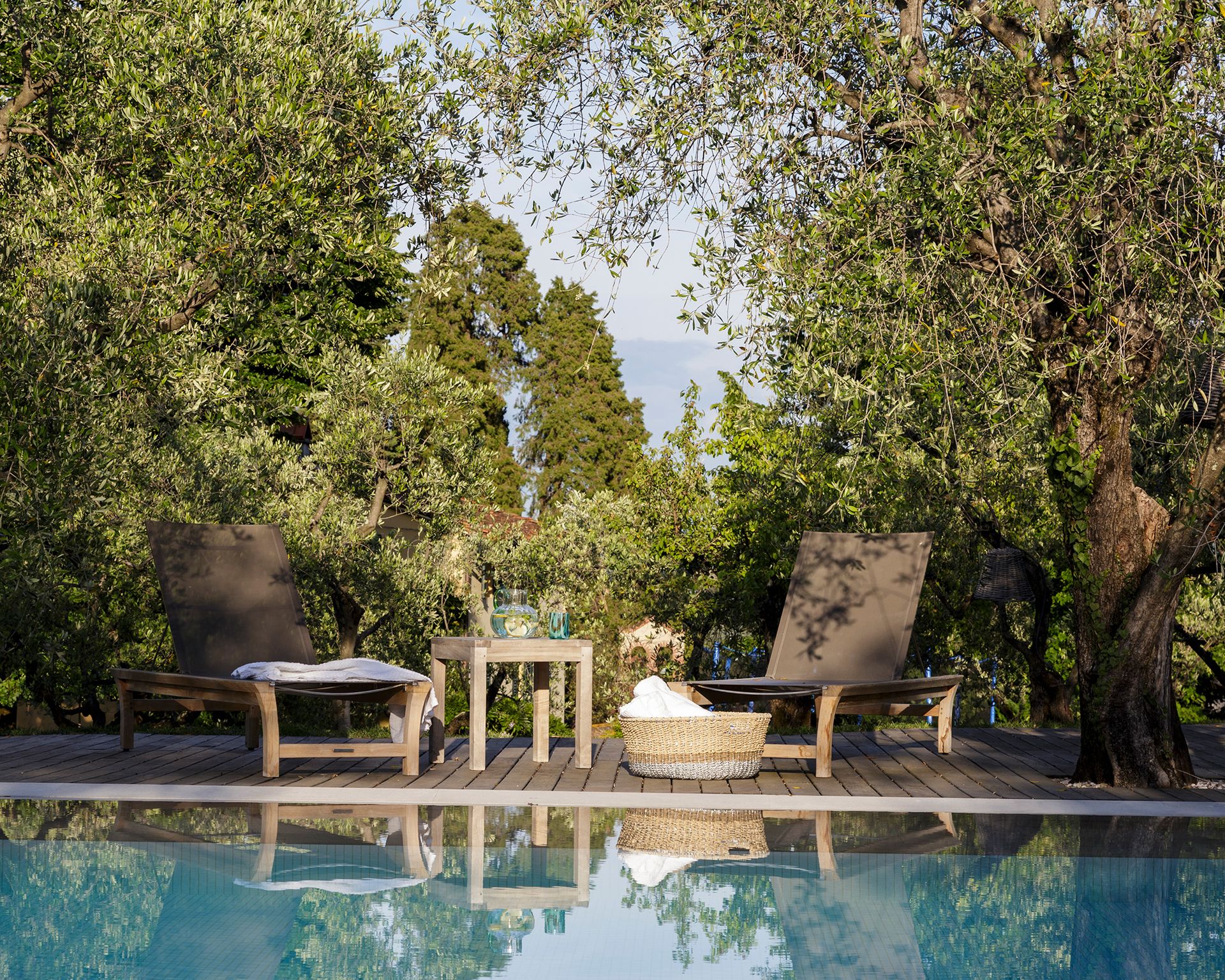 An example of pool party ideas showing a pool next to a decking area with two large sunloungers and a table