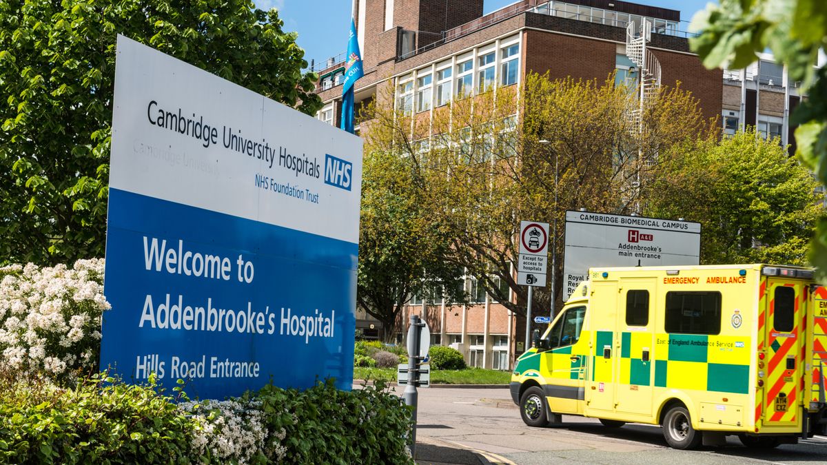 The entrance sign for Addenbrooke&amp;#039;s Hospital in Cambridge with an ambulance in background