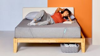 A woman with brown curly hair lies on the Siena Memory Foam Mattress