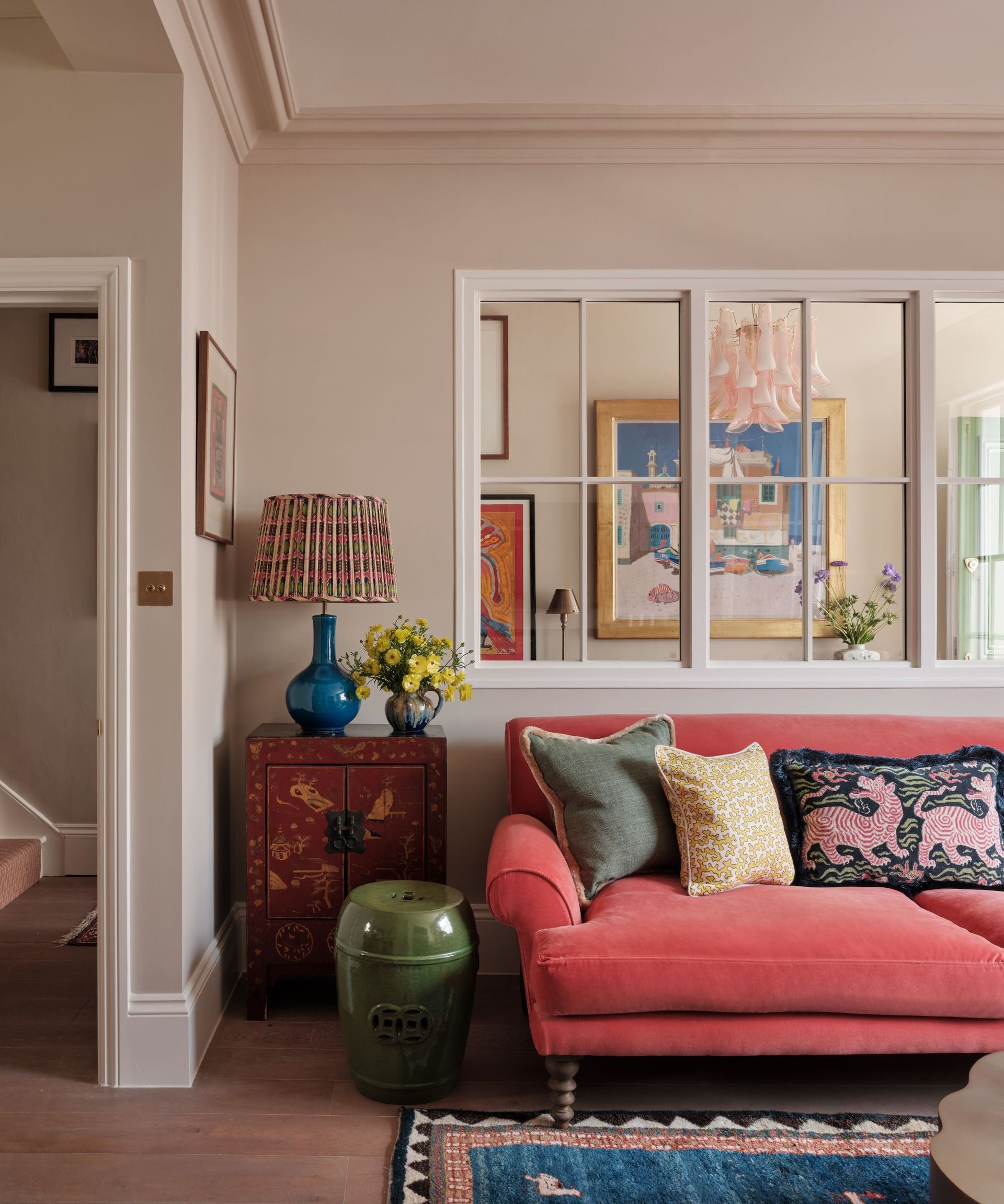Cozy living room with pink velvet sofa, rug, antique side table and pleated lamp