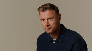 Freddie Flintoff in a dark shirt and looking towards the camera with a slight smile on his face 