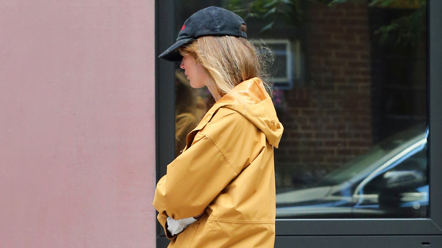 Jennifer Lawrence in NYC wearing a yellow windbreaker, red pants, boat shoes, and a black baseball cap