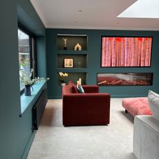 Infill extension that has become a media room - with large media wall, beige carpet and rust accent chair