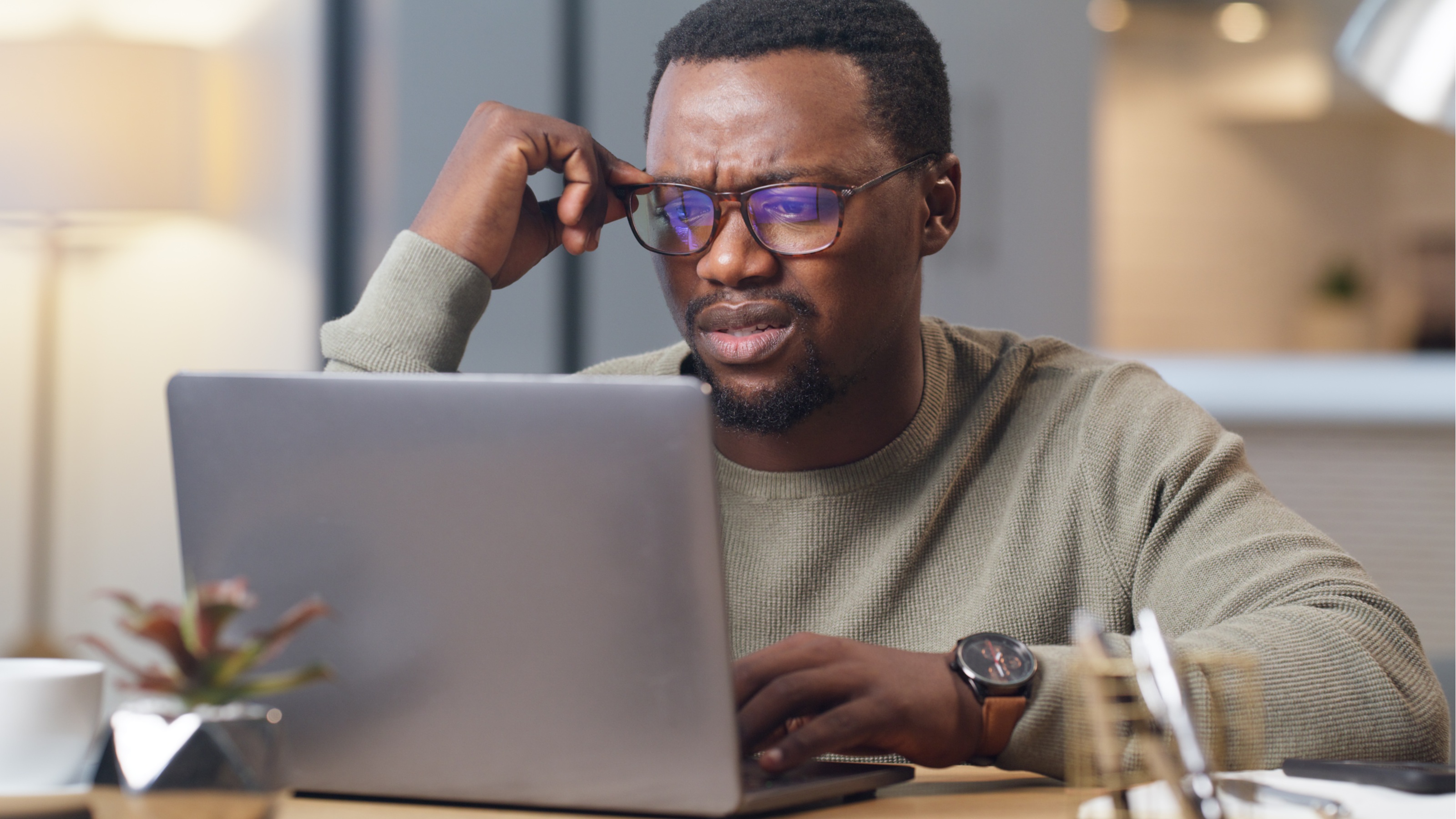 A middle-aged man looks stressed as he looks at his laptop at home.