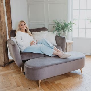 Stacey Solomon sitting on grey armchair with feet on matching storage footstool