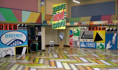 Interior view of unfurnished room with multiple coloured posters and paintings on wall