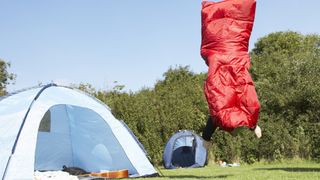 Camper in a sleeping bag leaping up in the air