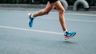 Man's legs with training shoes running on an empty road