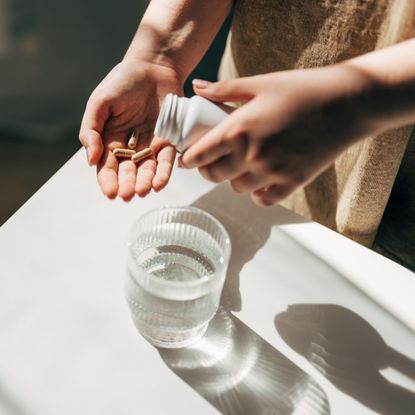 person putting supplements into their hand ready to take