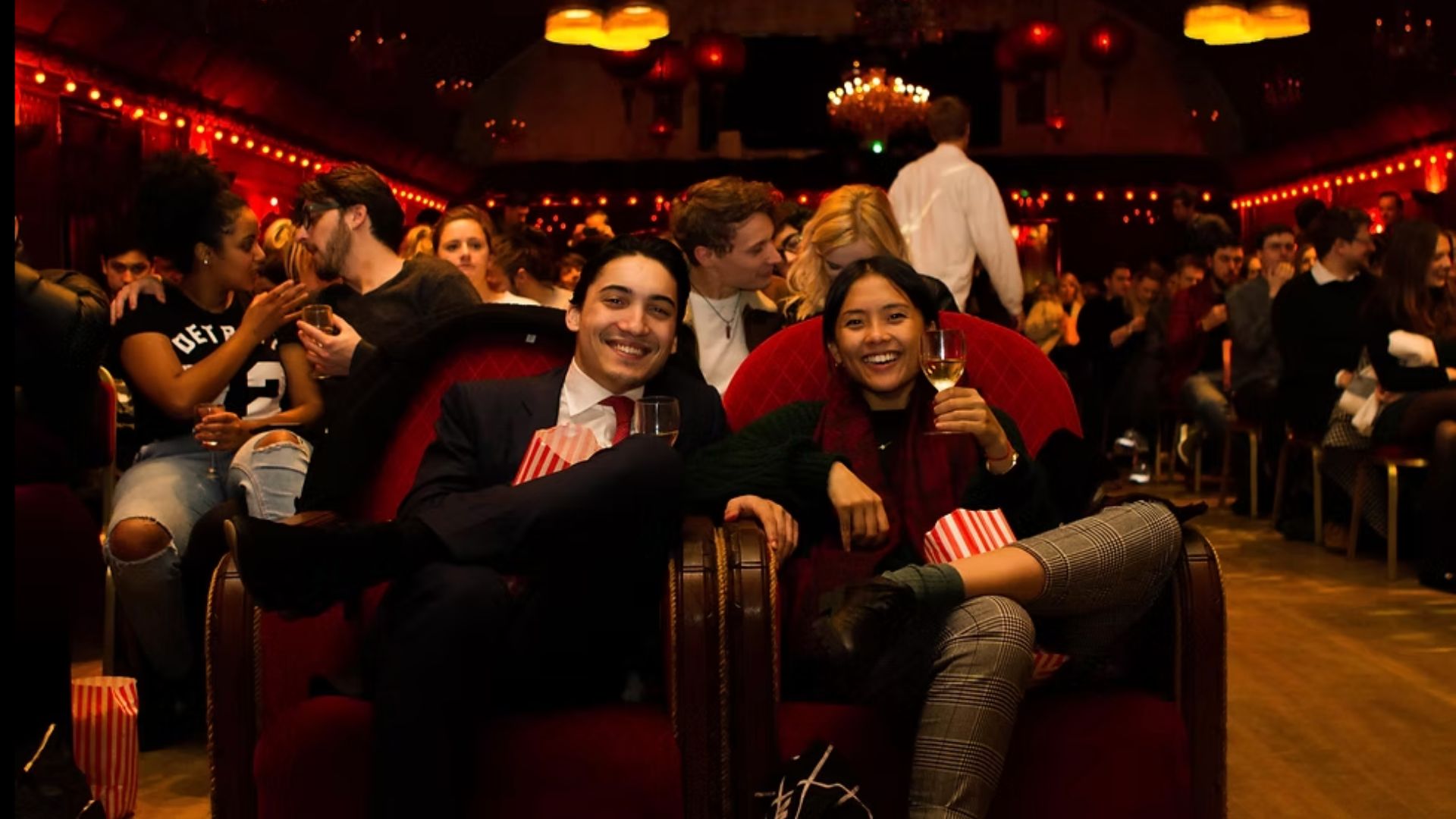 an image of a man and a woman sitting on an old fashion double sofa in the ballroom during a cinema night