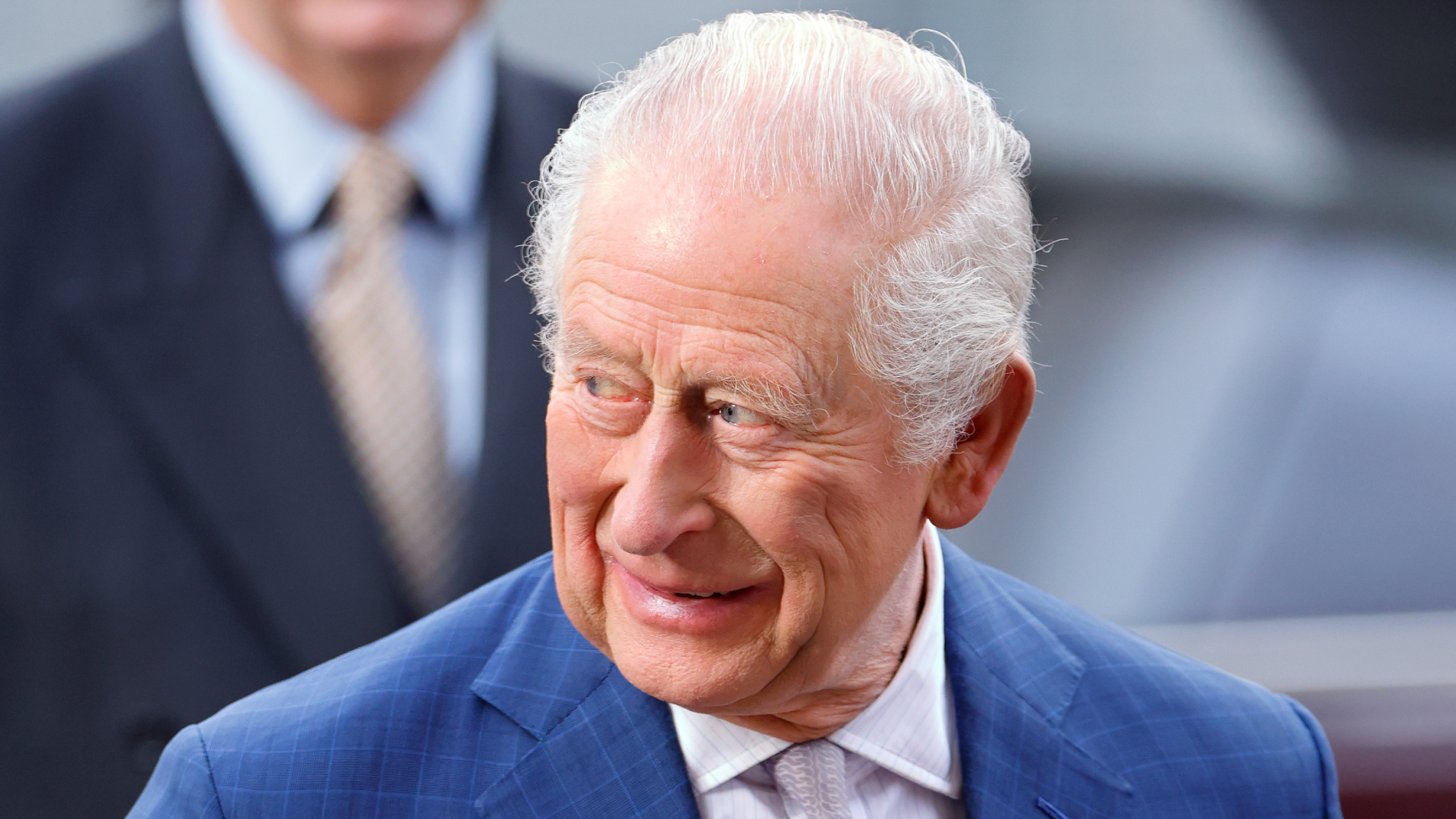 King Charles wearing a blue suit and smiling