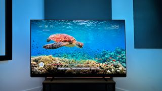 Philips OLED909 OLED TV in darkened room showing Ambilight bias lighting with turtle on screen