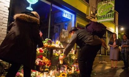 Mourners add to a memorial of beer, candles, and flowers in front of Cafe Racer in Seattle, where a gunman, Ian L. Stawicki, shot five people earlier that morning, four of whom died. 