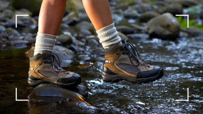 Woman walking across muddy stream in socks and hiking boots after learning how to keep your feet warm on a hike