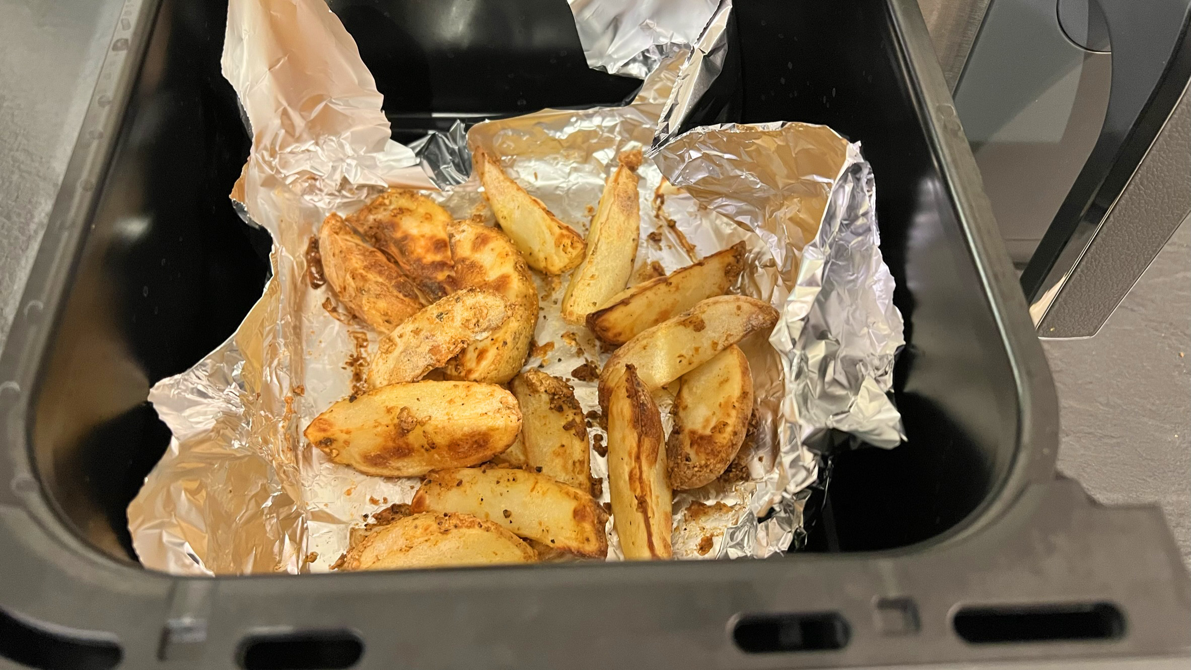 Cooked potato wedges in a deep fryer basket