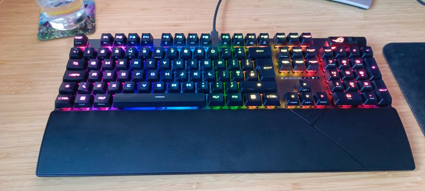 A black ASUS ROG Strix Scope II RX gaming keyboard on a wooden desk