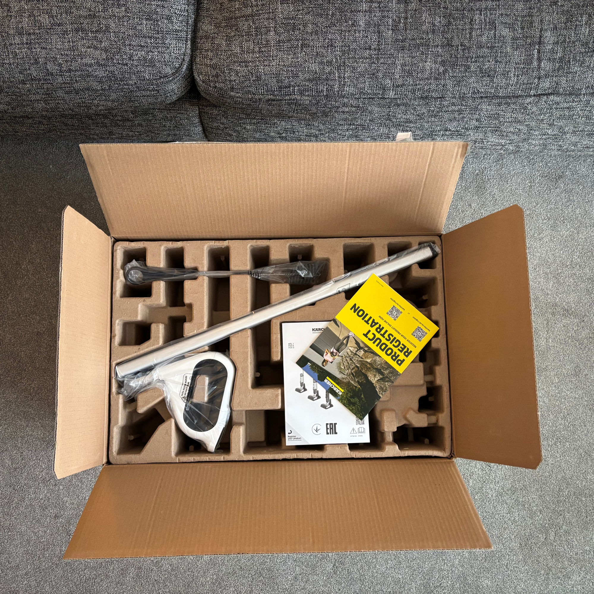 Overhead view of opened packaging showing accessories slotted on a layer of cardboard