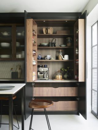 pocket doors conceal wooden drawers and cabinetry with coffee machine and other appliances within