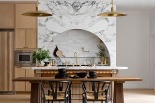 a wood and marble kitchen with an arched hood