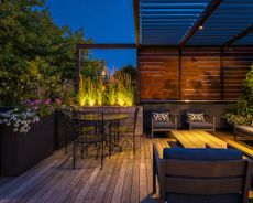 A rooftop deck at night with lighting and planters
