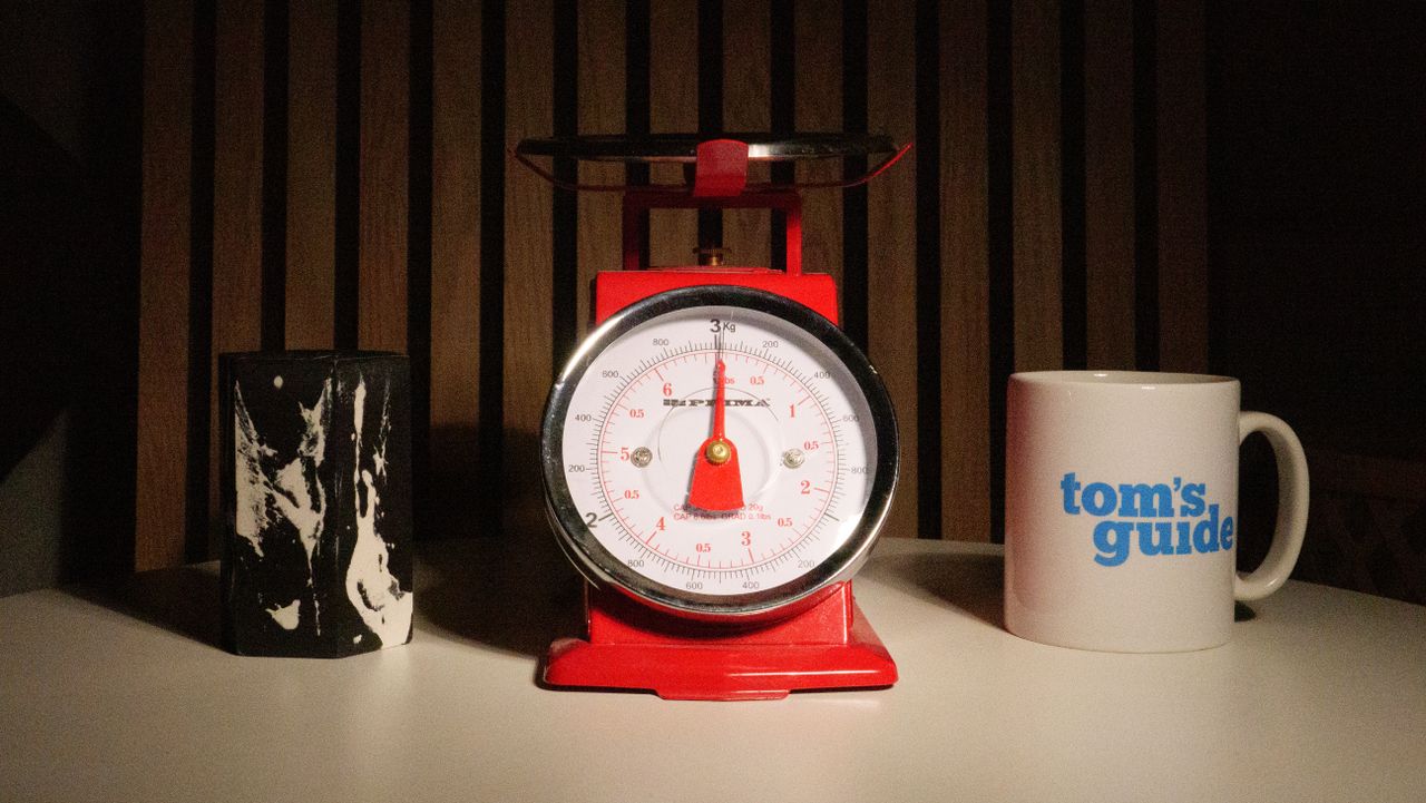 A photo of a set of red scales next to a Tom's Guide mug