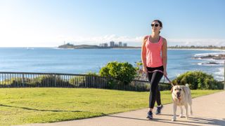 Woman walking dog on leash on Australia’s Sunshine Coast