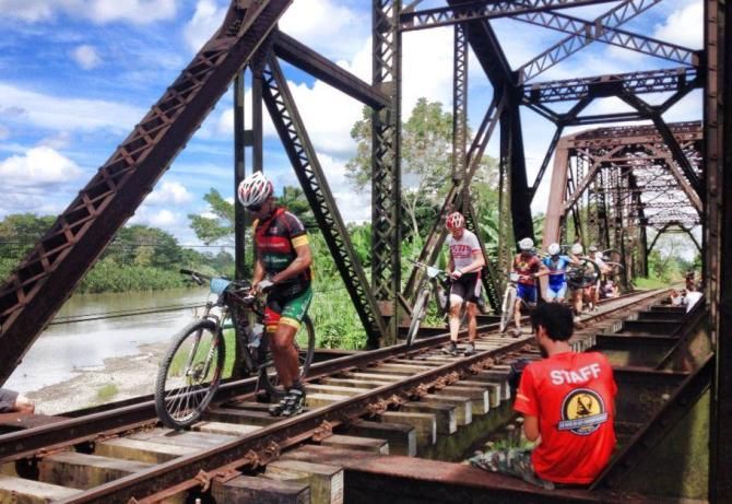 The top elite men cross a railroad bridge in stage 3
