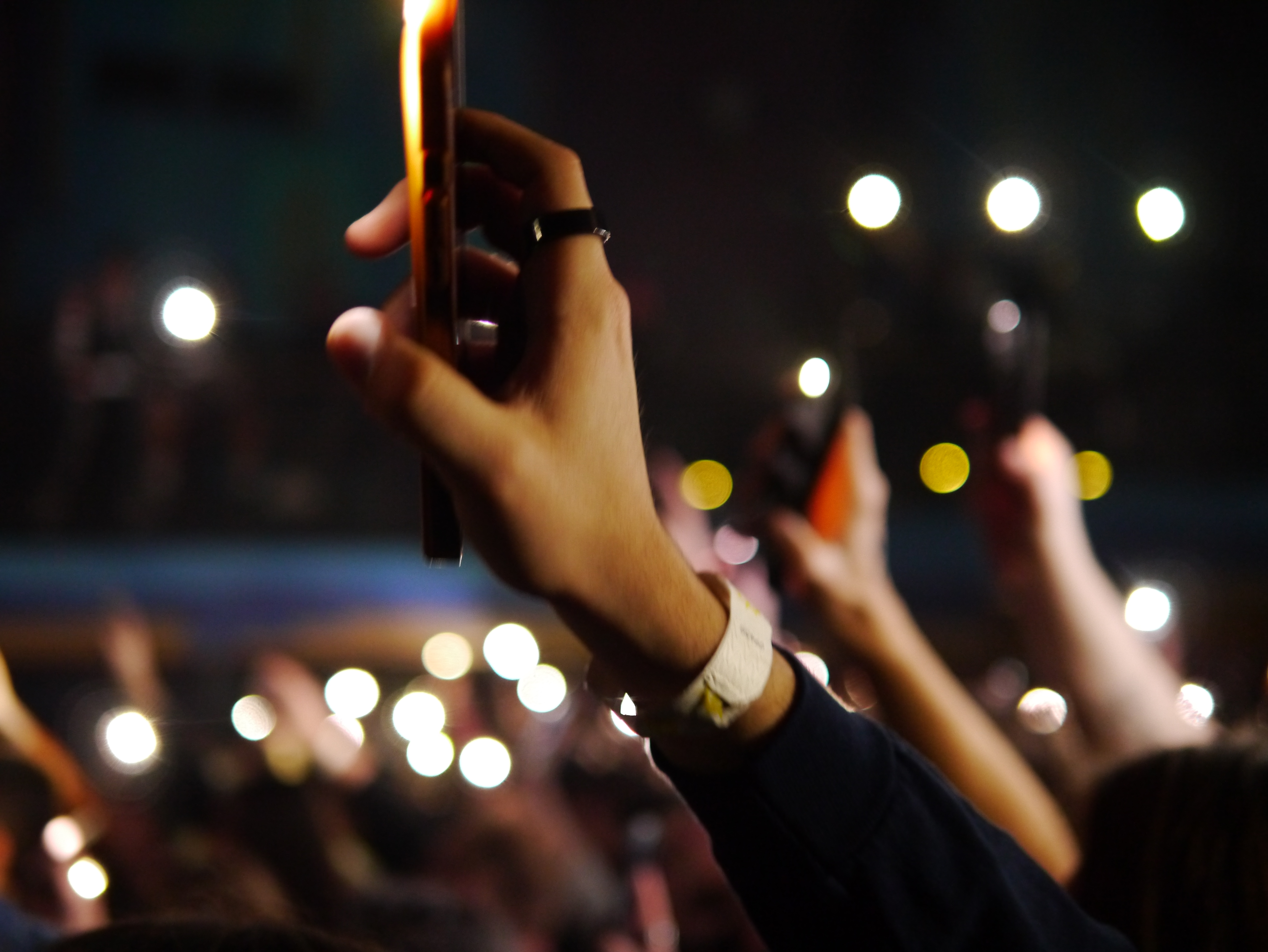 A hand in the air holding a smartphone at a concert