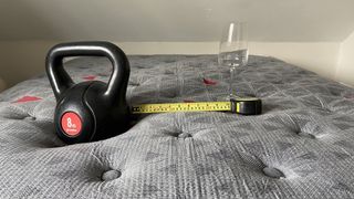 Zoma Boost mattress with a weight, tape measure and wine glass on it