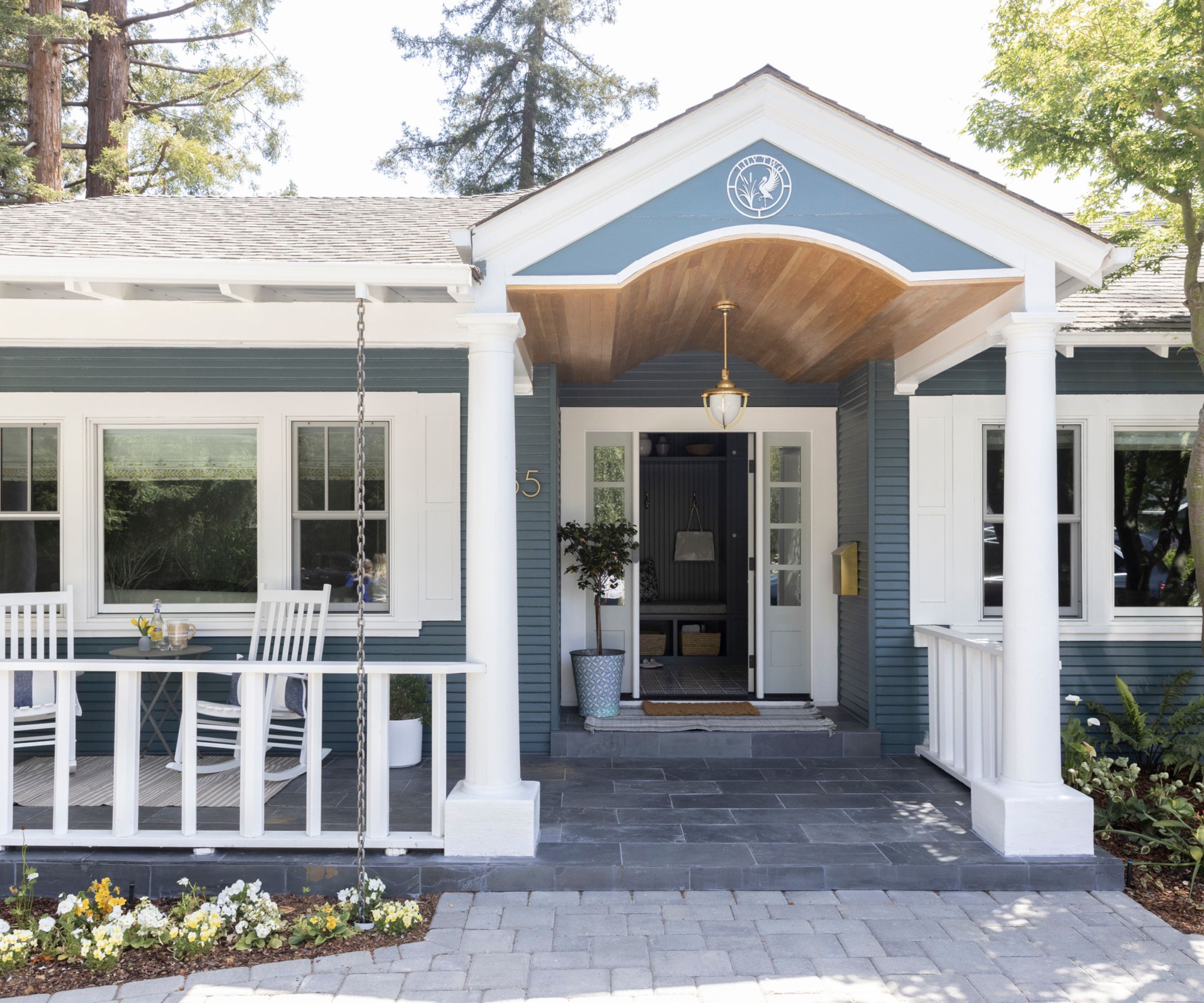Traditional house with columns and white fence, porch with two rocking chairs and front door